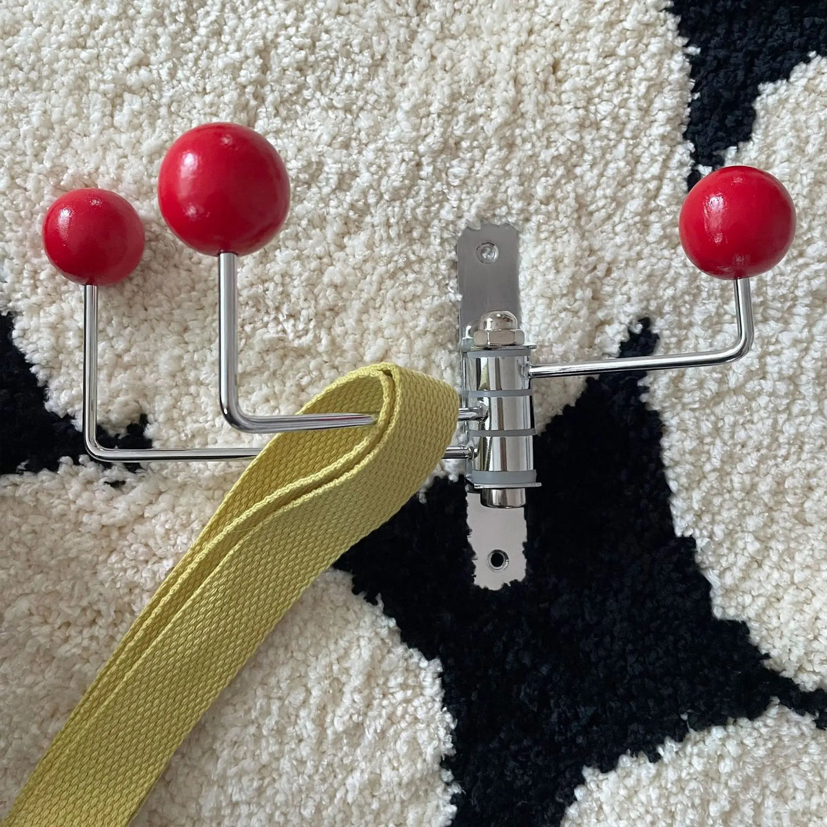 Vintage rotating iron coat hook in red on a patterned rug