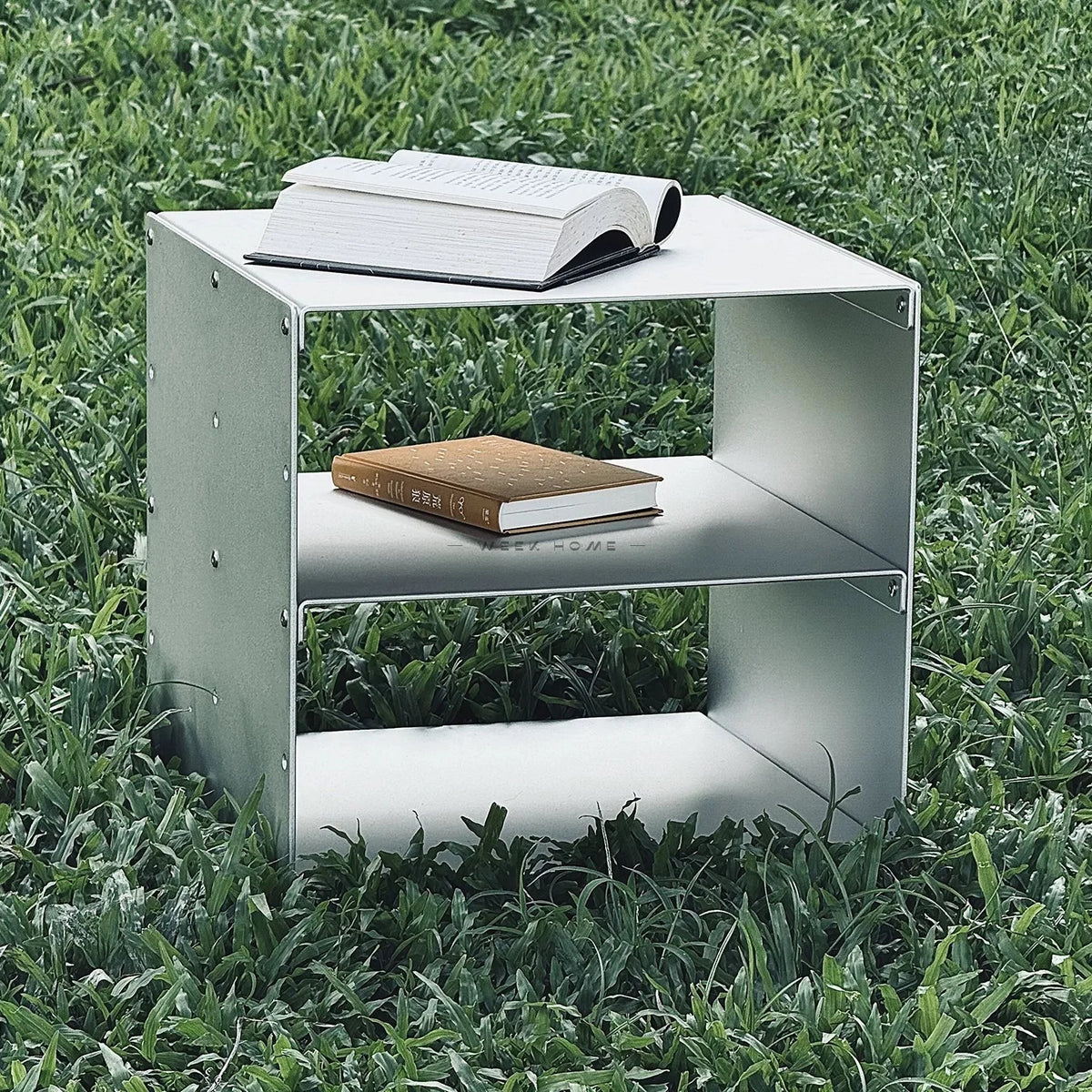 Bauhaus Modular Stainless Steel Shelf on a green lawn with a book