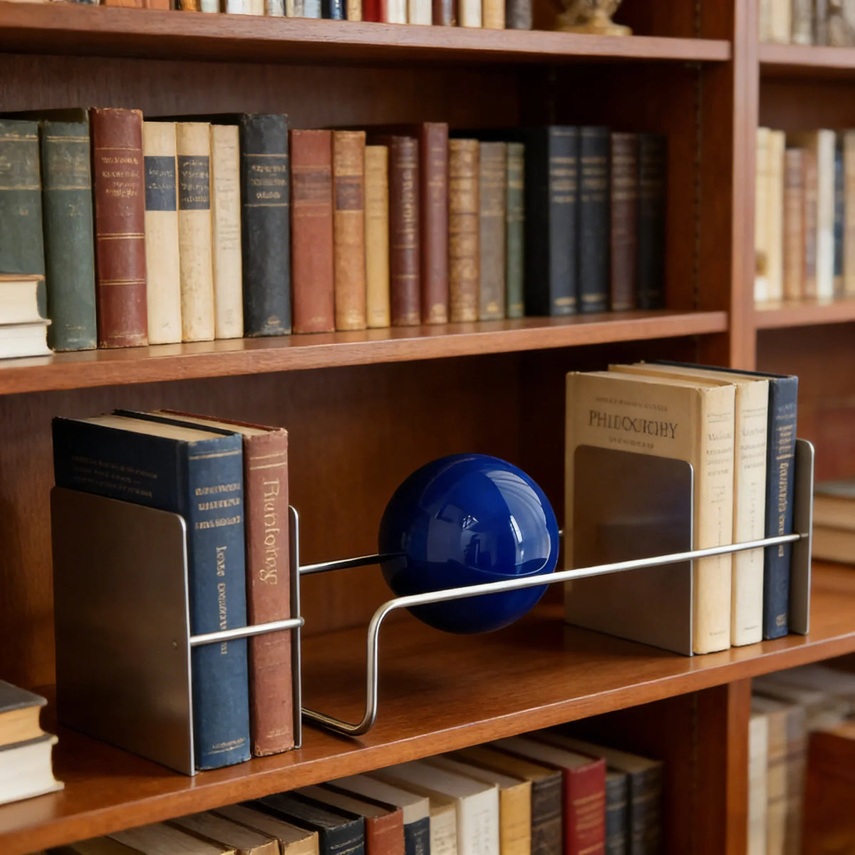 Sculptural Metal Desktop Organiser with a blue sphere on a bookshelf